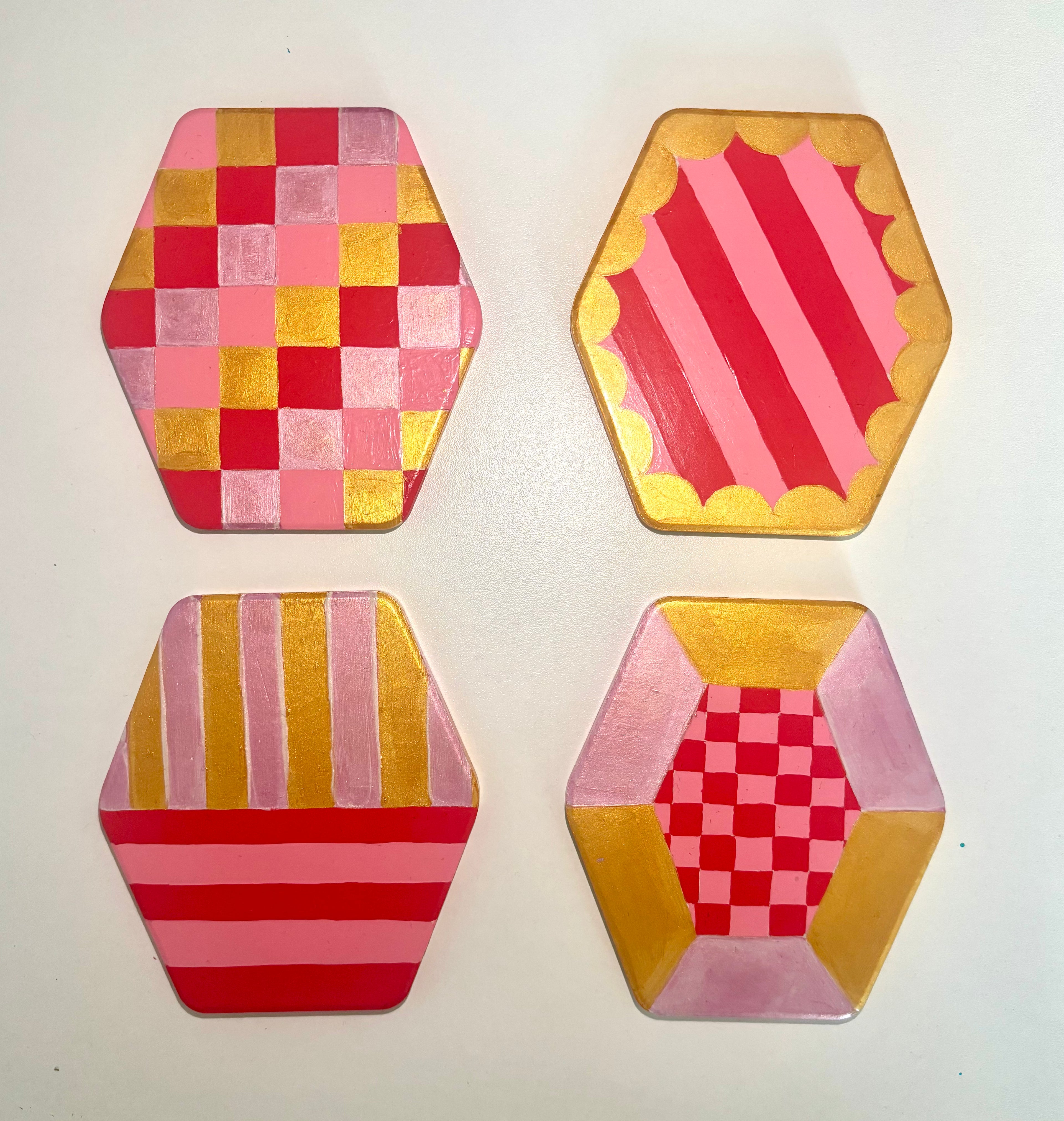 Set of 4 geometric pink and gold coasters, hexagonal shape.
